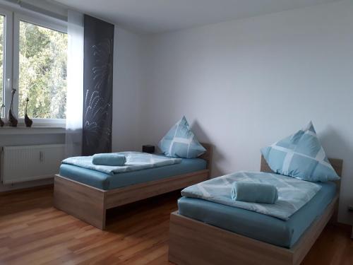 two beds with blue pillows in a room with a window at Ferienwohnung SimBlick in Simmerath