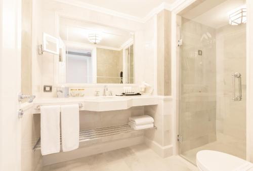a white bathroom with a sink and a mirror at Metropolitan Hotels Taksim in Istanbul