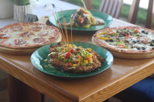 a table with four pizzas on plates on it at Banan Serviced Apartments & بنان للشقق المخدومه in Tabuk