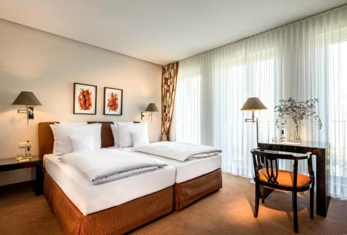 a bedroom with a large bed and a chair at Parkhotel Bremen – ein Mitglied der Hommage Luxury Hotels Collection in Bremen
