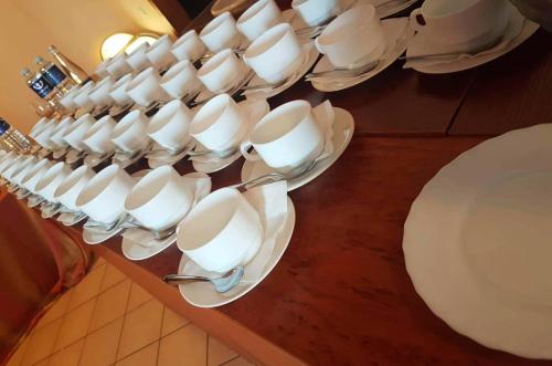 a bunch of white cups and plates on a table at Pasienis in Pasvaliečiai
