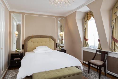 a bedroom with a large bed and a chandelier at Badrutt's Palace Hotel St Moritz in St. Moritz