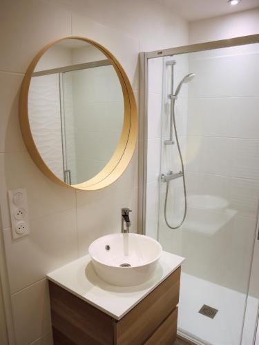 une salle de bain avec un lavabo et une douche avec un miroir dans l'établissement Lutin Vue Baie La Baule - Appartement T2 design et connecté, à La Baule