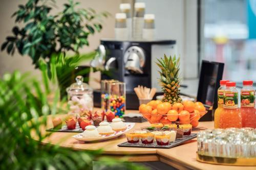 a table with food and drinks and fruit on it at Residence Mercure Paris La Defense Grande Arche in Nanterre