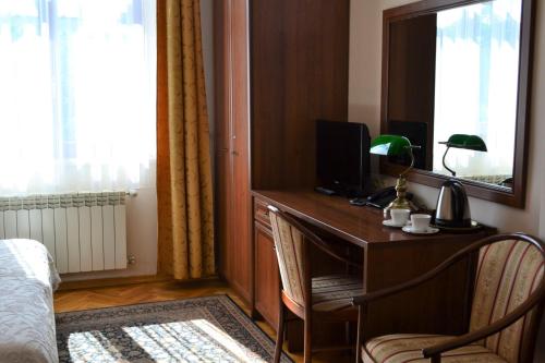 a bedroom with a desk with a television and a bed at Aparthotel Basztowa in Krakow