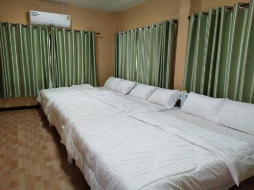 a large white bed in a room with green curtains at 19th house in Ban Nong Sa