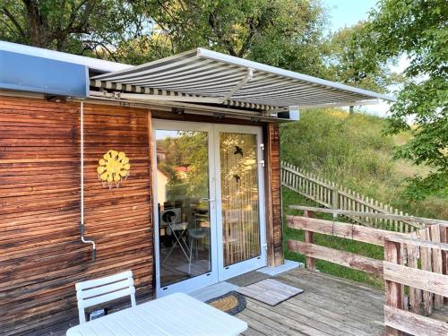 a wooden house with awning and a table on a deck at Tiny House mit Klima und Heizung, in idyllischer Ortsrandlage in Iba