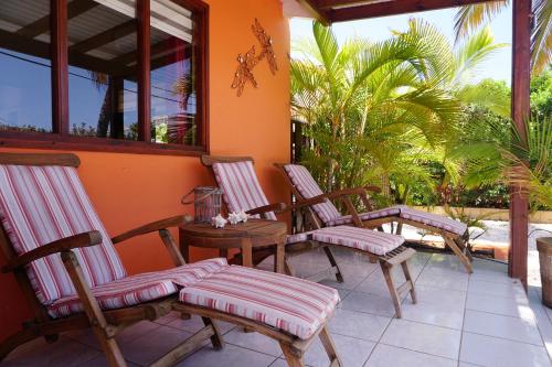 a porch with chairs and a table and palm trees at Cariñas Studio Apartments in Palm-Eagle Beach