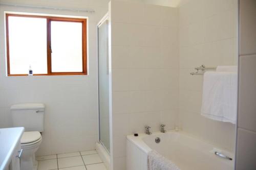a white bathroom with a tub and a toilet at Vrede Fountain House Farm Stay in Graaff-Reinet