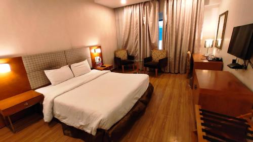 a bedroom with a large white bed and a desk at Best Western Ashoka in Hyderabad
