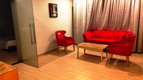 a room with a red couch and two chairs and a table at Best Western Ashoka in Hyderabad