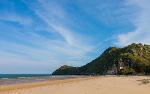 a beach with a mountain in the distance at Nam Talay Resort in Pran Buri