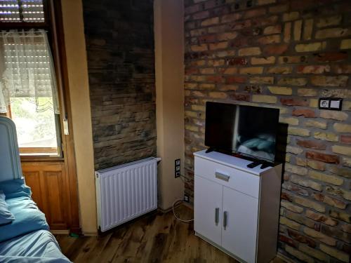 a living room with a tv on a brick wall at Fortuna Vendégház in Kiskunhalas
