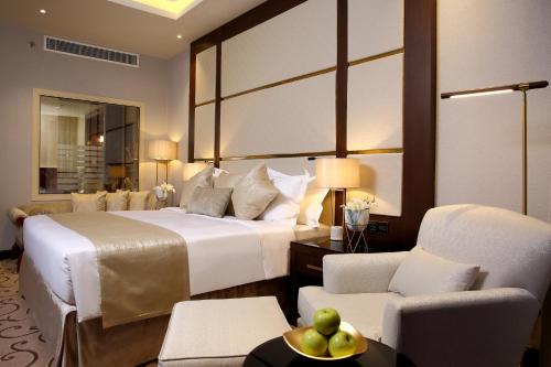 a hotel room with a large bed and chairs at Vittori Palace Hotel and Residences in Riyadh
