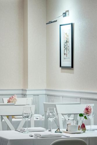 a dining room with white tables and chairs with wine glasses at Villa Źródło & Spa in Krynica Zdrój