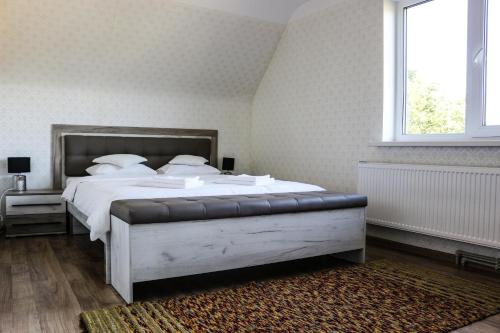 a bedroom with a bed with white sheets and a window at Krusttēvu māja in Sigulda