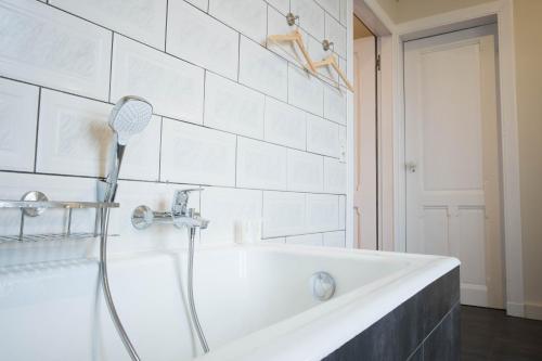 El baño incluye bañera blanca con cabezal de ducha. en Castle ten Berghe Château, en Brujas