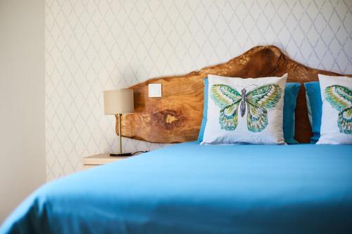 a bedroom with a bed with blue sheets and butterfly pillows at Quinta do Lordelo Turismo Rural in Penafiel