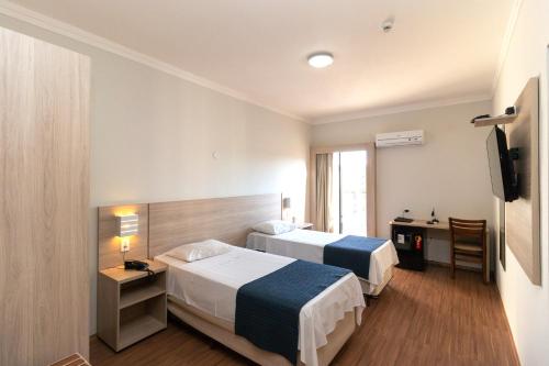 a hotel room with two beds and a desk at Bristol Zaniboni Mogi Mirim in Mogi Mirim