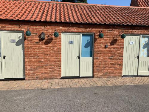 a brick building with three doors and a red roof at The Olive in Market Rasen