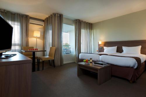 a hotel room with a large bed and a television at Résidence la Réserve Genève Ferney Voltaire in Ferney-Voltaire