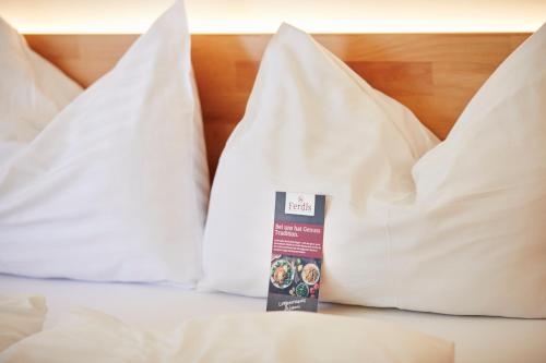 a bed with white sheets and a box of pillows at I AM HOTEL Graz-Seiersberg in Graz