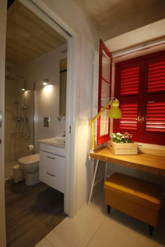 uma casa de banho com um lavatório, um WC e uma janela vermelha em Valletta Central Suites em Valletta