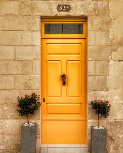 an orange door on a building with two plants at Valletta Central Suites in Valletta