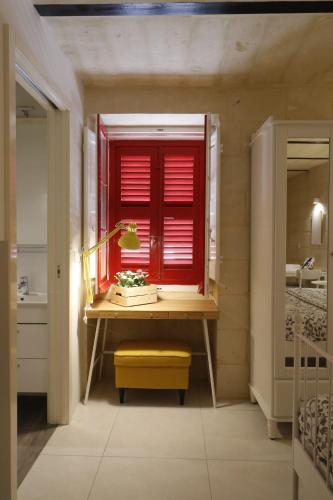 uma casa de banho com uma janela vermelha e uma secretária com um banco amarelo em Valletta Central Suites em Valeta