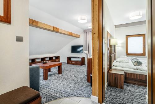 a hotel room with a bed and a tv at Villa Źródło & Spa in Krynica Zdrój
