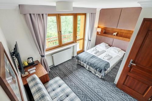 クリニツァ・ズドルイにあるVilla Źródło & Spaのベッドとソファ付きのホテルルーム