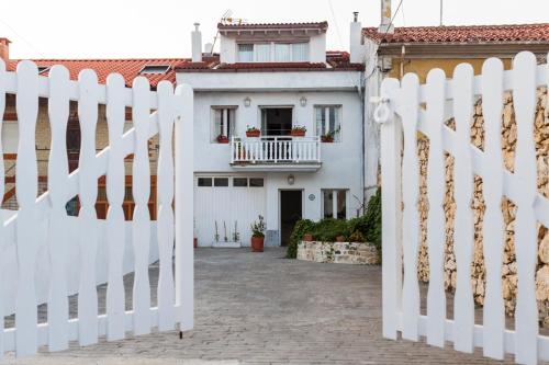 einen weißen Zaun vor einem weißen Haus in der Unterkunft Habitaciones Estrella del Norte in Santander