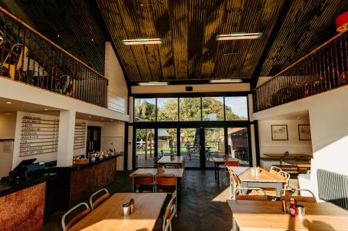 a restaurant with wooden ceilings and tables and chairs at Creeksea Place Barns in Burnham-on-Crouch