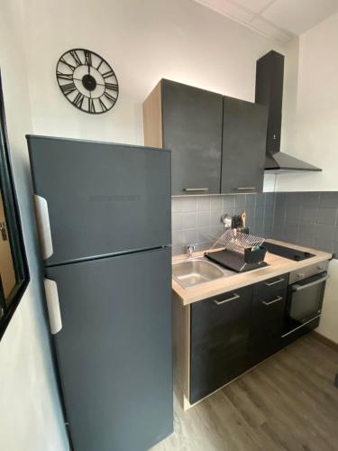 La cuisine est équipée d'un réfrigérateur, d'un évier et d'une horloge. dans l'établissement Studio meublé en Centre Ville avec vue sur la Dent du Chat, à Aix-les-Bains