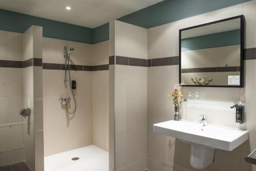 a bathroom with a sink and a shower and a mirror at Hôtel Le Bristol in Avignon