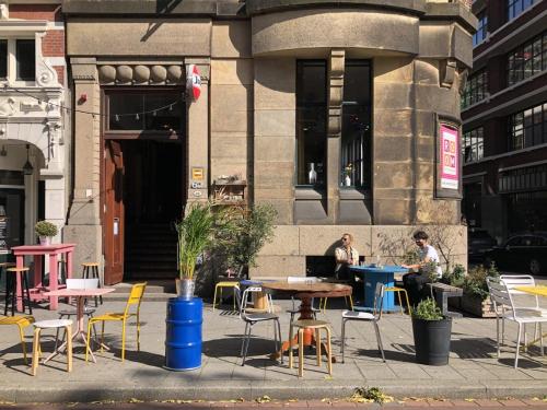 a group of tables and chairs in front of a building at Hostel ROOM Rotterdam in Rotterdam