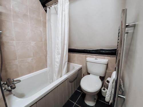 a bathroom with a toilet and a tub and a sink at The Blenheim Buttery in Woodstock