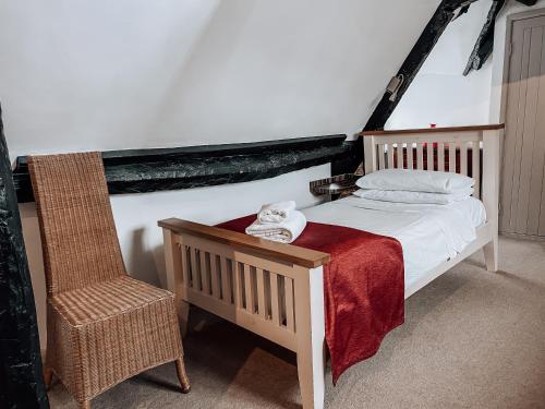 a bedroom with a white bed and a chair at The Blenheim Buttery in Woodstock