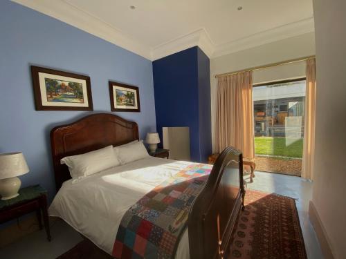 a blue bedroom with a bed and a window at The Welgemoed Guest House in Bellville