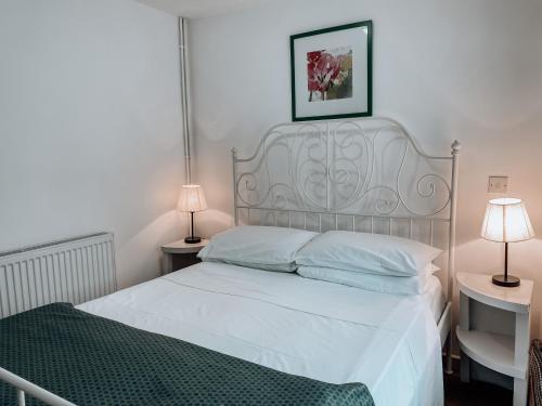 a bedroom with a white bed with two lamps at The Blenheim Buttery in Woodstock