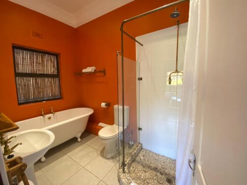 a bathroom with a tub and a toilet and a sink at The Welgemoed Guest House in Bellville