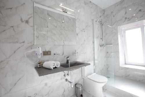 a white bathroom with a sink and a toilet at Kulikovskiy hotel in Kharkiv