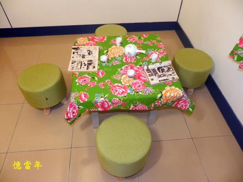 a table with green chairs and a table with flowers at Ting Yi B & B in Taitung City