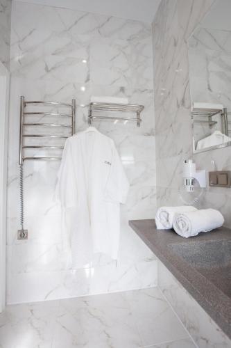 a white bathroom with a sink and towels on a counter at Kulikovskiy hotel in Kharkiv