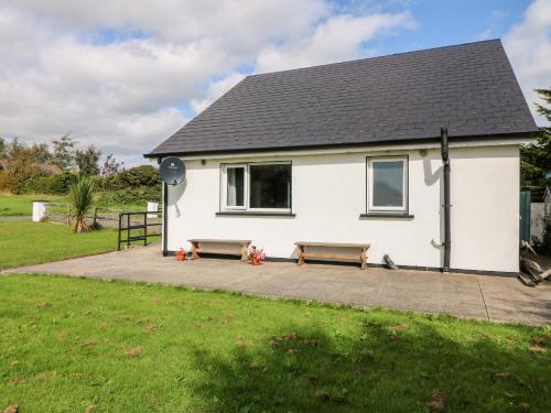a white house with two benches in front of it at SeaChange Annexe in Ballygarrett