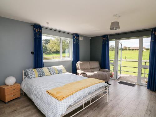 a bedroom with a bed and a chair and a window at SeaChange Annexe in Ballygarrett