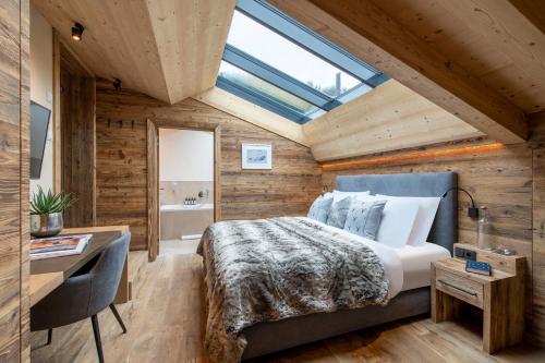 a bedroom with a bed and a desk and a window at Brunnenhof Luxury Apartments in Lech am Arlberg