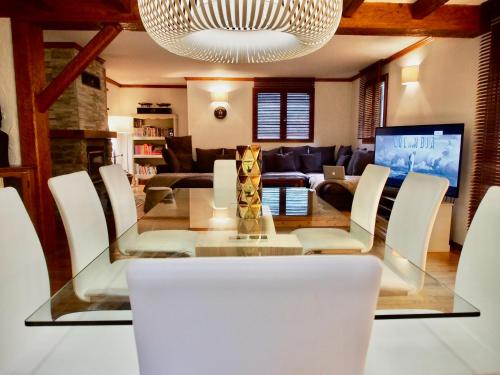 a dining room with a glass table and white chairs at Chalet Greystone in Brides-les-Bains