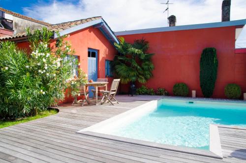 a backyard with a swimming pool and a red house at La Ferrade Chambres d'Hôtes B&B in Bègles