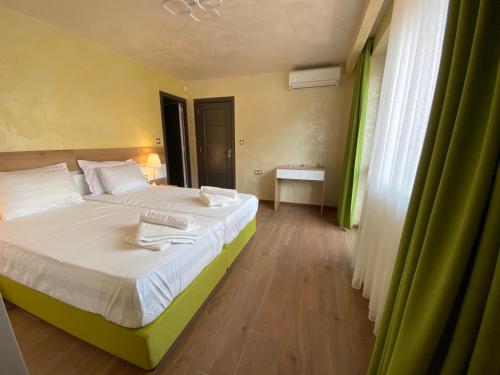 a bedroom with a bed with white sheets and green curtains at Amazing view and cozy atmosphere in Veliko Tŭrnovo